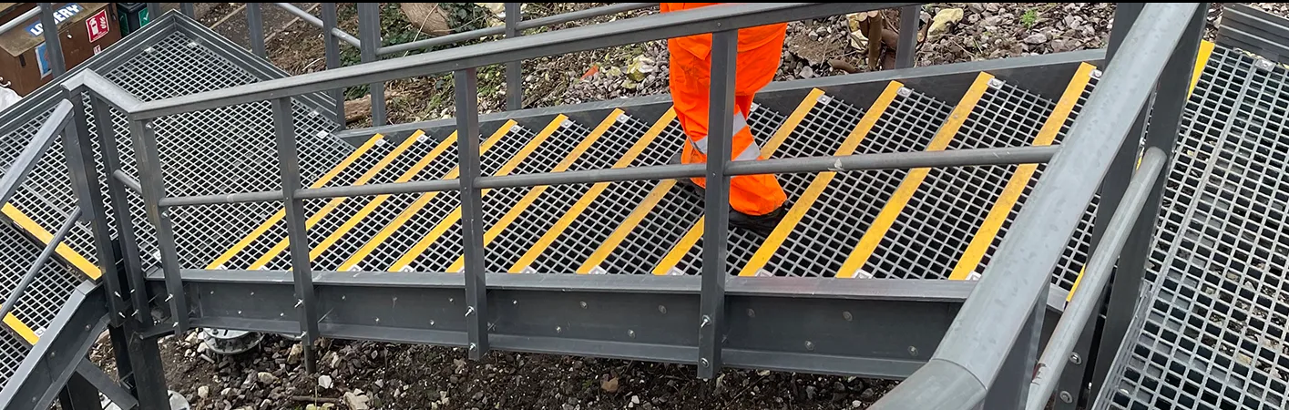 GRP-trappa med halksäkra trappsteg och kantskydd GRP-trappa med halksäkra trappsteg och gula kantmarkeringar i industrimiljö